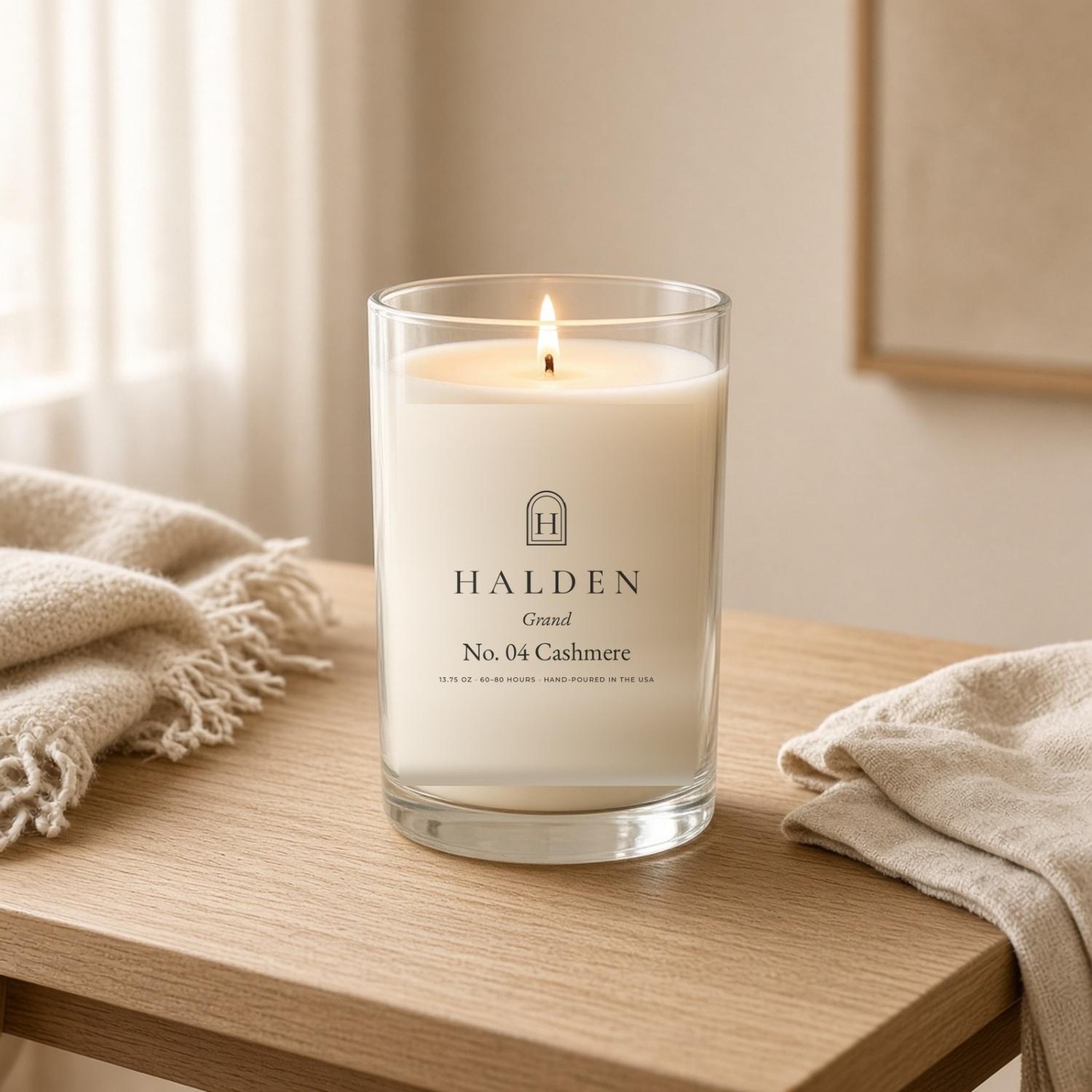 Lit Halden Cashmere Grand candle on an oak table beside a wool throw